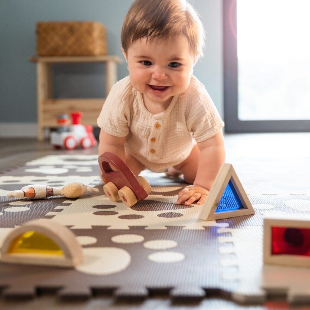 Cute happy baby boy playing toys in his child room